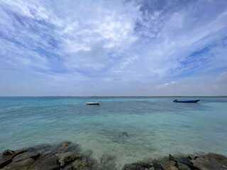 Wide angle shot of two fishing boats on the tuquoise water of the Caribbean Sea on the island of Bonaire under a blue sky with clouds