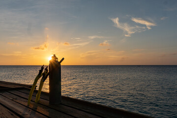 Rays of a setting sun behind snorkel gear- fin, tank, mask, and snorkel with copy space