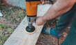 A man is using power tool to polish wooden plank