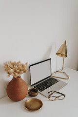 Wall Mural - Laptop with blank copy space screen on table with stationery on table against white wall. Minimalist home office workspace. Mockup template