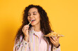 © New Africa - African American woman eating French fries on yellow background