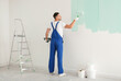© New Africa - Man painting wall with light blue dye indoors