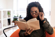 Confused black lady in glasses trying to read book
