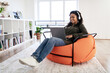 © Prostock-studio - Smiling black woman in headset using laptop at home