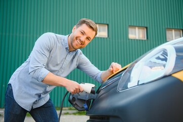 Man charging his electric car at charge station.