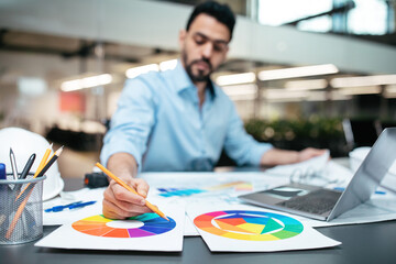 Wall Mural - Busy concentrated smart attractive millennial arab guy designer with beard in shirt working on project at table