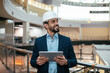 © Prostock-studio - Cheerful millennial islamic guy engineer with beard in hard hat, suit checks project on tablet, looks at free space