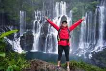 Happy Hiker With Red Jacket In Front Of A Waterfall