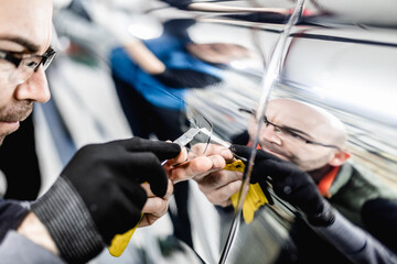 Wall Mural - Car wrapping specialists putting silver mirror chrome foil on car. Selective focus.