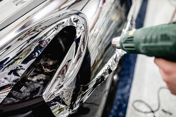 Wall Mural - Car wrapping specialist putting silver mirror chrome foil on car. Selective focus.