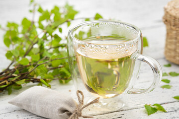 Wall Mural - Healthy herbal tea cup, twigs of Birch tree with leaves. Alternative herbal medicine.