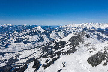 Wall Mural - View from a drone on a winter mountains covered with forests and snow in Alps and small villages