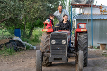 Selective Focus Shot Of Mom Driving Tractor And Grandpa And Little Girl Walking Around On Tractor.