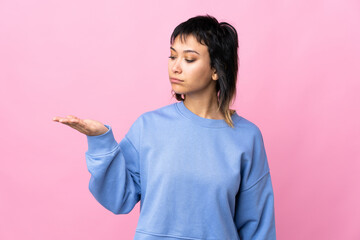 Wall Mural - Young Uruguayan woman over isolated pink background holding copyspace with doubts