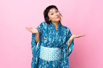 Wall Mural - Young woman wearing kimono over isolated blue background making doubts gesture