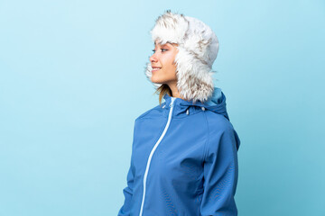 Wall Mural - Young Uruguayan girl with winter hat isolated on blue background looking to the side