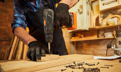 Wall Mural - Senior carpenter with drilling instrument working in the carpentry workshop to make a piece of furniture