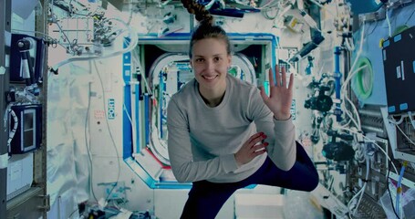 Wall Mural - female astronaut waving to camera inside the international space station. iss. some elements of the 