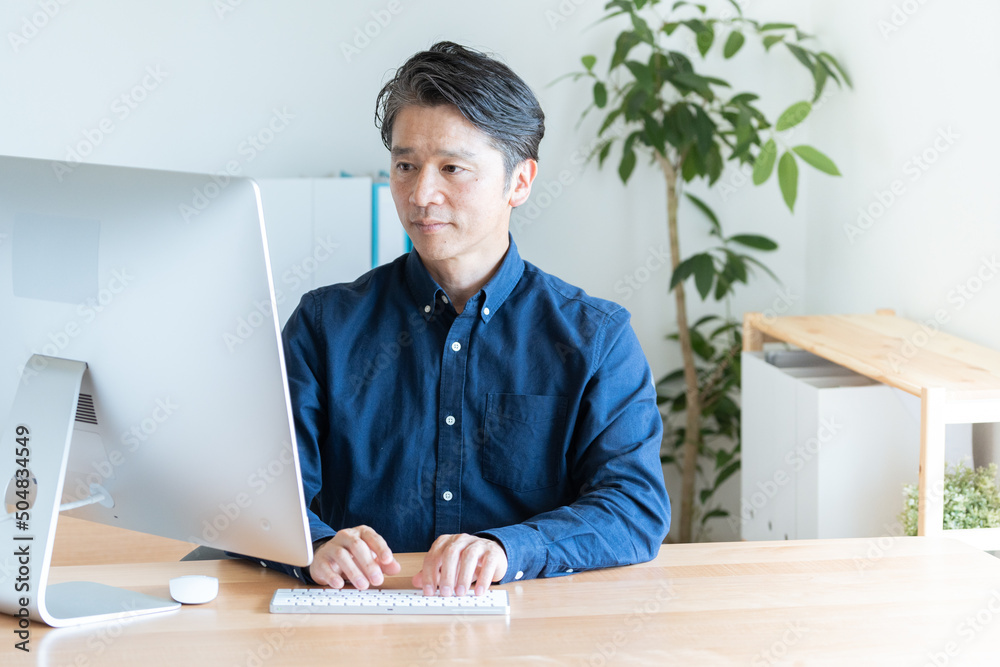 デスクトップパソコンを使うビジネスマン（ビジネス・カジュアル・ミドル男性）