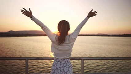 Wall Mural - B roll - Happy freedom traveler woman relaxing with raised arms on the bridge at sunset, Enjoy travel concept. Watching the sunset with beautiful landscape