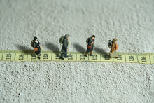 Miniature People Toy Figure Photography. A Group Of Person Walking Above Measuring Tape. Distance Traveled Concept
