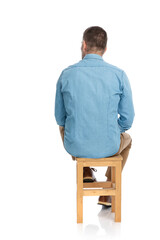 Wall Mural - back view of grizzled hair man in denim shirt sitting on wooden chair