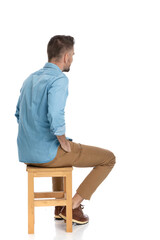 Wall Mural - bearded casual guy sitting on chair and holding hands in pockets