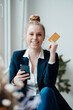 © Westend61 - Smiling businesswoman holding credit card and smart phone at office