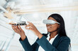 © Westend61 - Smiling businesswoman wearing virtual reality simulator holding machine part in factory