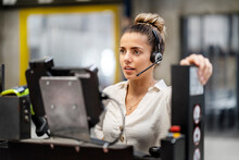 Young Businesswoman Wearing Headset Operating Machine In Factory