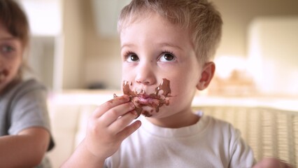 children eat chocolate. dirty little baby kids in the kitchen eating chocolate in the morning. happy