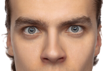 Closeup male blue eyes of young handsome man isolated on white studio background. Concept of men's health, vision, self-care, medicine and cosmetics.