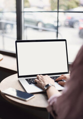 Young woman using laptop computer with blank white screen at cafe. Business woman working in modern office. Freelance lifestyle, e-learning, studying, web site, technology and online shopping concept