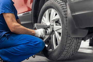 Wall Mural - Concept car wheel service. Professional mechanic changing tires