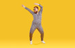 Cheerful funny eccentric fat man in good mood is dancing and fooling around on orange background. Overweight bearded man dressed in leopard print jumpsuit is dancing and fooling around. Full length.