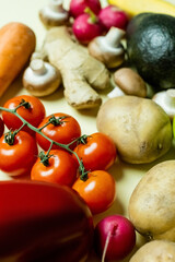 Wall Mural - Close up view of fresh cherry tomatoes near blurred vegetables on yellow background.