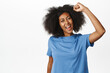 © Cookie Studio - Enthusiastic african american woman cheering, raising clenched fist in support, protesting, fighting human rights, cheering or rooting, standing over white background