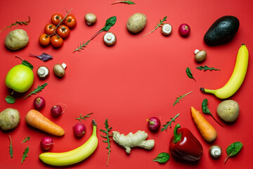 Wall Mural - Flat lay with frame from fresh vegetables and fruits on red background.