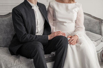 Canvas Print - the groom in a suit with the bride in a wedding dress sit on the sofa