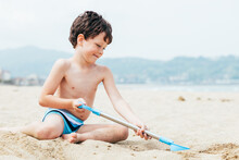 Glad Little Boy Digging Sand On Beach