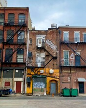 Urban Scene Of Old City Apartment Buildings With Graffiti And Fire Escapes. Rear Of Building. Back Doors And Trash Cans. Center City Philadelphia Pennsylvania.