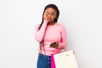 young adult black woman feeling bored, frustrated and sleepy after a tiresome. shopping bags concept