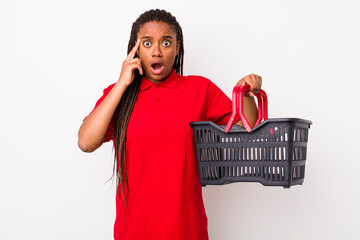 Wall Mural - young adult black woman looking surprised, realizing a new thought, idea or concept. empty shopping basket concept