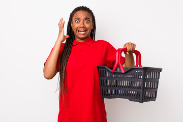 Wall Mural - young adult black woman screaming with hands up in the air. empty shopping basket concept