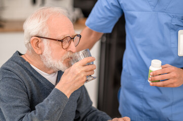 Wall Mural - Aged man taking medications supervised by a healthcare worker