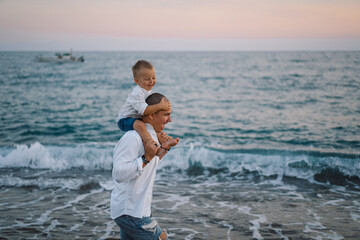 Wall Mural - Happy Father's day. Father and baby play on the beach. Dad and him Child together enjoying sunset. Loving single father hugs cute little son.