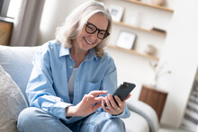 Pleasant Mature Lady Resting On Couch, Using Applications On Smartphone, Chatting In Messenger Or Social Network
