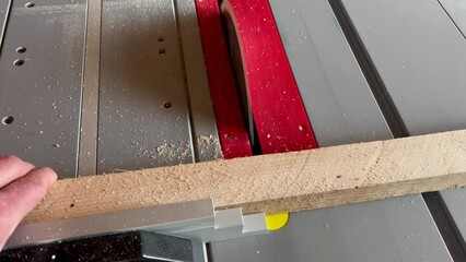 Sticker - Carpenter cross cutting a piece of recycled pine wood board at the table saw.