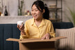 © Prostock-studio - Happy Asian woman unpacking parcel after online shopping