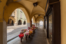Busca, Cuneo, Italy - May 13, 2022: Ancient Historical Arcades Of Via Umberto I With Display Of Flowers From The Shop